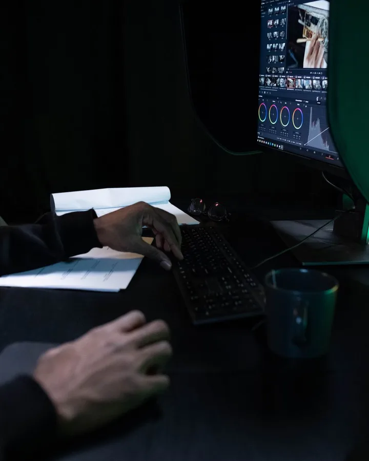 A retouching desk in close-up, screen light on the surface.